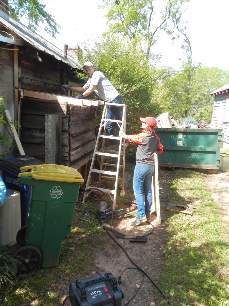 Sean Griffith and Rebekah Helfgot work to replace the roof and siding of a small addition on the shotgun house.