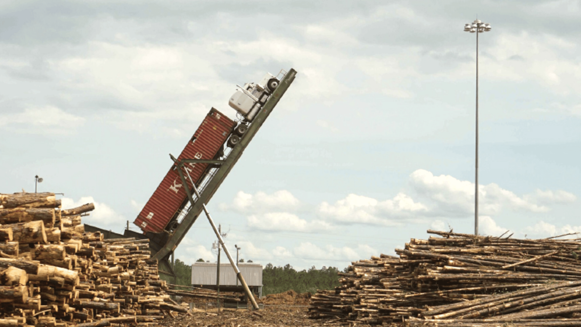 A semi truck is held upside down surrounded by lumber