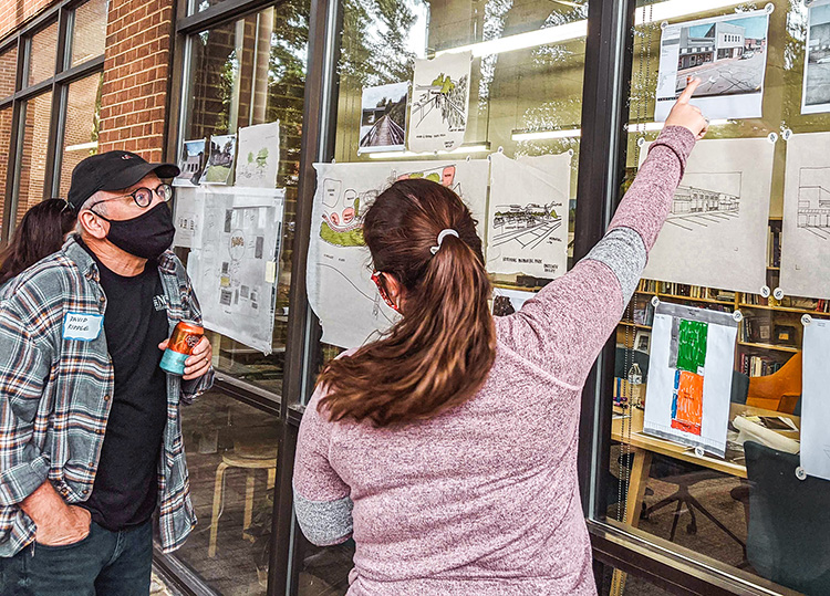 A person points at design charrettes for a brewpub in Hawkinsville to show another person.