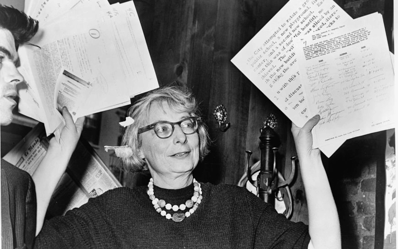 Picture of Jane Jacobs holding papers up in the air.