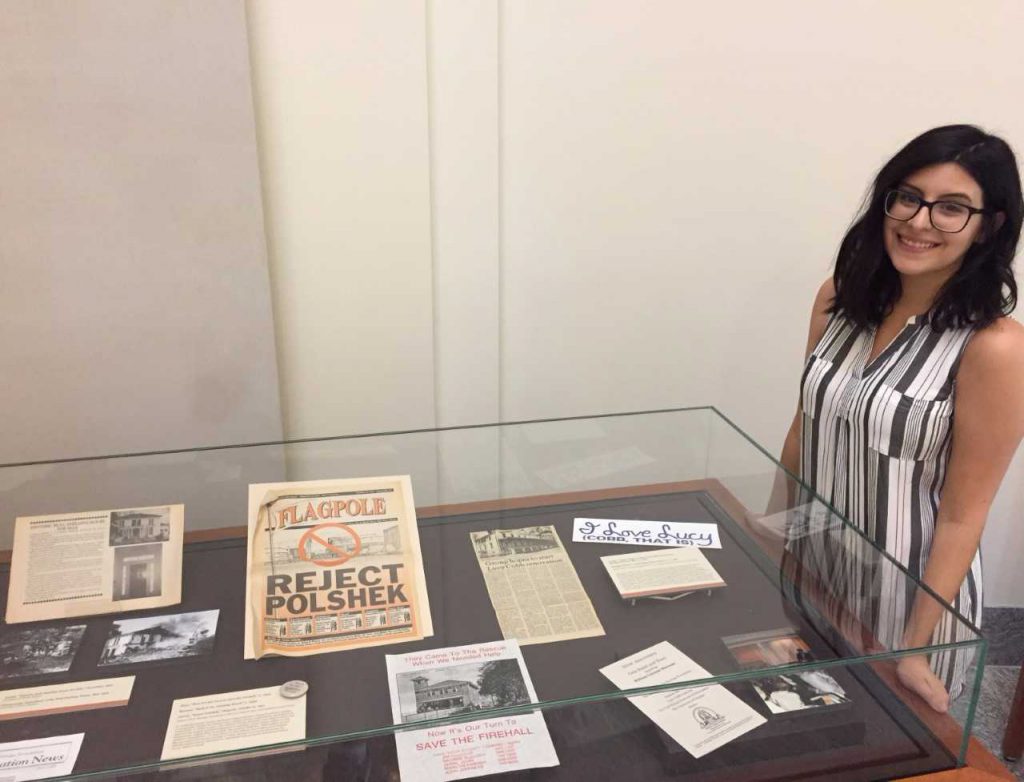 Lisa Demarais Kirby poses with one of the displays at the exhibit she created at the Special Collections Library celebrating the 50th anniversary of ACHF.