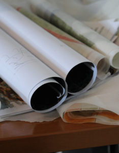 Designs of urban planning assignments are rolled into tubes and set on a table.