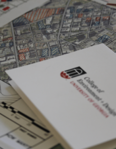 Picture of a UGA CED card with urban planning designs in the background.
