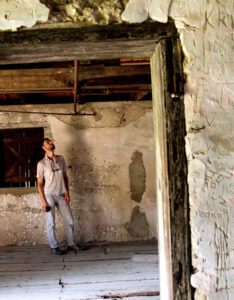 Student inspecting the interior of an old, deteriorated building.