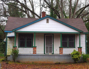 Front view of a small single-story house with a covered porch and green trim.