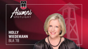 A headshot of a smiling blonde woman is on the right, with "Alumni SPOTLIGHT" and a UGA logo in the top left, and the text "HOLLY WIEDEMANN BLA '78" in the bottom left, all on a dark red background.